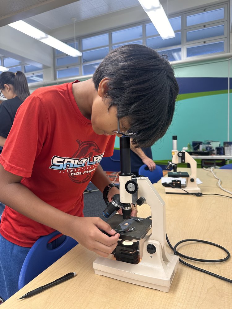A Salt Lake Elementary student looking through a light microscope